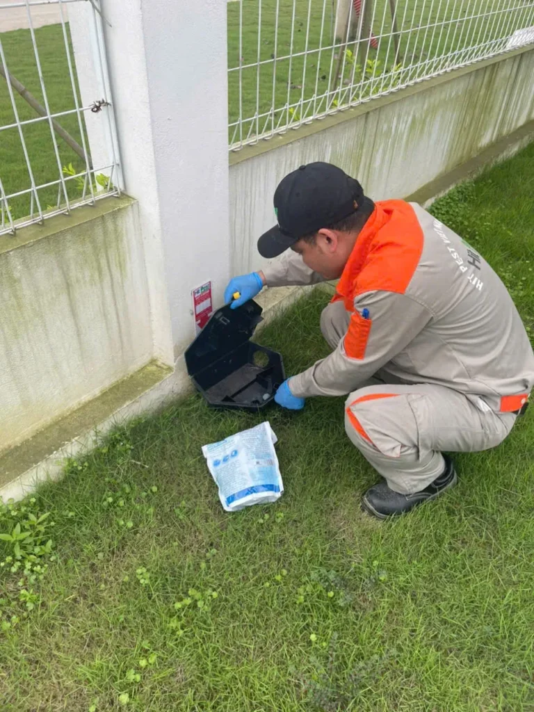 Kỹ thuật viên HIT PEST thao tác với hộp trạm kiểm soát chuột tại hàng rào công trình